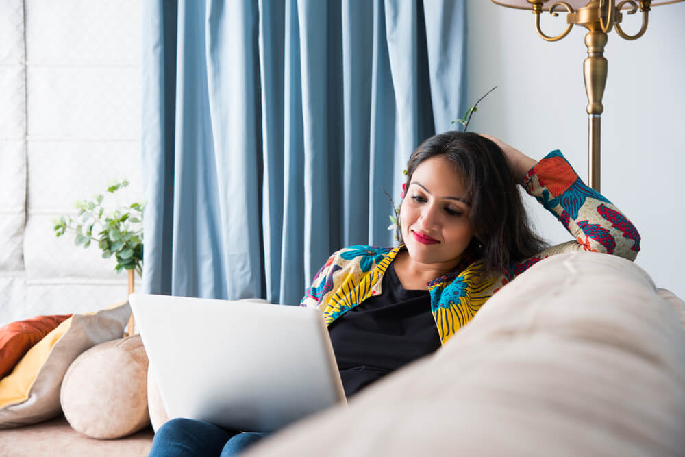 girl or woman using laptop sitting on sofa