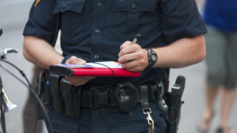 A close-up of a police officer writing out a traffic ticket for a moving violation.