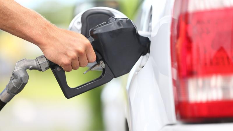 A man pumping gas into his white car.